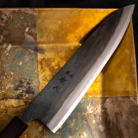 Close-up of the Kurouchi finish on the Kokugei Gyuto Aogami #1 Kuro-uchi Ebony 210mm, highlighting the rustic black surface texture and handcrafted aesthetic.