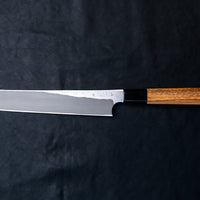 Nigara Kurozome Kiritsuke Yanagiba Aogami #2 Damascus 240mm (9.4") is a traditional single-bevel Japanese knife used for preparing meat and raw fish, especially sashimi and nigiri sushi, and meat. Its length allows the user to slice different types of protein in one single pulling motion, that will – together with the razor-sharp single bevel blade – birth smooth, shiny cuts.