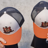 SharpEdge exclusive merch: SharpEdge x Vincent Trinidad Trucker Hat Exclusive SharpEdge design of a brown sumo-fighting bear, armed with our ZDP-189 Bunka Black Japanese knife in collaboration with artist Vincent Trinidad. The bottom of the sturdy visor features the SharpEdge logo within a Japanese rising sun.