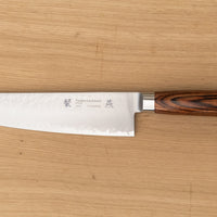 Kengata refers to the shape of the blade similar in usage to a Chef’s knife, but with a more striking look. The blade is finished off with a reversed tanto tip (also known as K-tip). The profile and length are suitable for both long and short cuts, the curve of the belly enables chopping on a kitchen board and the sharp tip excels at tasks where precision is key. The core of the blade has a high-polish finish and is forged out of VG-5 steel .