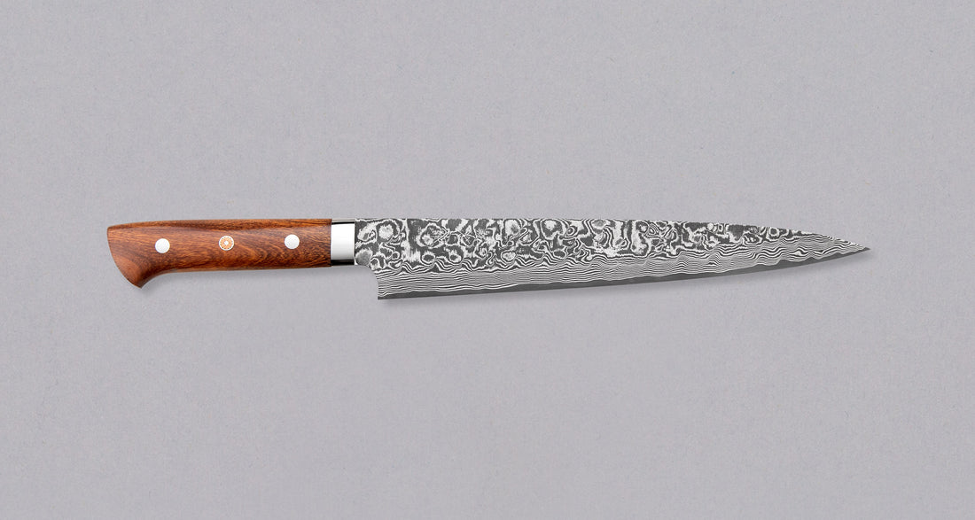 Saji Sujihiki Rainbow Damascus 240mm (9.5") is definitely not just a looker. The core is made of R2/SG2 powder steel, tempered to 63-64 HRC, clad into layers of rust-resistant stainless steel, to which nickel was added to get a unique dark Damascus pattern. Fitted with an ironwood handle. A great example of usable art!