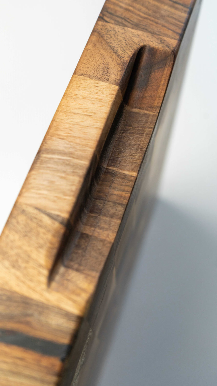 end grain walnut cutting board, handmade in Slovenia. Pictured: side of the board with the carved handle.