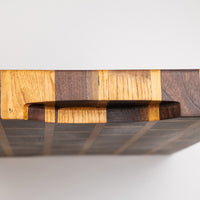 This cutting board is made of American walnut and oak wood. In comparison to edge grain boards, end grain cutting boards are gentler to the knife's edge and have a "self-healing" property - the wood fibers close up after they have been cut, making the board more antibacterial. Natural mineral oil (50ml) is included.