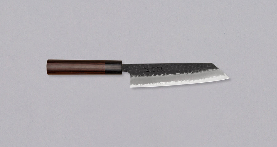 Hokiyama Bunka AS Kurouchi 170mm (6.7") is a multi-purpose knife that will handle all sorts of cutting techniques and is great for preparing fish, meat, and vegetables. Its Aogami Super steel core is protected with san-mai lamination. Fitted with an oval Japanese wa handle, made of rosewood.