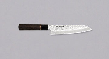 Kawamura Santoku Damascus is a multi-purpose Japanese kitchen knife. The core is made out of stainless AUS-10 steel, wrapped in layers of Damascus steel and the top part of the blade is adorned with hammer prints. The traditional Japanese handle is made out of burnt chestnut wood with a buffalo horn ferrule.