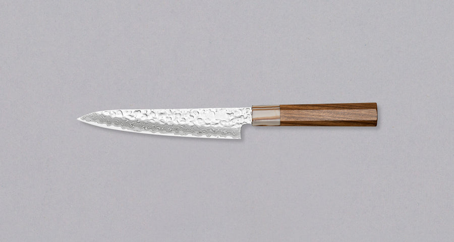 The Kotetsu VG-10 Damascus Petty 150 mm is a small Janapese knife with visible hammer prints, a damascus pattern and a classic Japanese (wa-style) teak handle. VG-10 stainless steel ensures rust resistance, durability, and wear resistance. Because it is low-maintenance, it is suitable as a first Japanese kitchen knife.