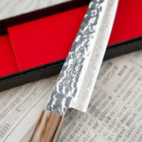 The Kotetsu VG-10 Damascus Petty 150 mm is a small Janapese knife with visible hammer prints, a damascus pattern and a classic Japanese (wa-style) teak handle. VG-10 stainless steel ensures rust resistance, durability, and wear resistance. Because it is low-maintenance, it is suitable as a first Japanese kitchen knife.