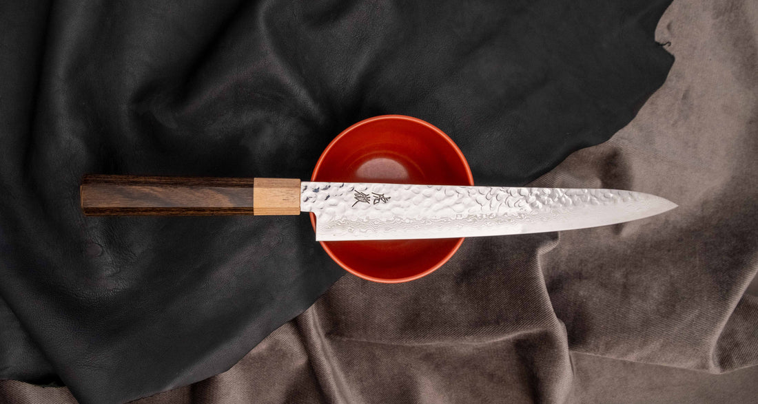 The Kotetsu Sujihiki VG-10 Damascus 240mm (9.5") is a long and narrow Japanese slicer with visible hammer prints, a damascus pattern, and a classic Japanese (wa-style) pakka wood handle. It will impress anyone who appreciates aesthetically designed kitchen utensils.