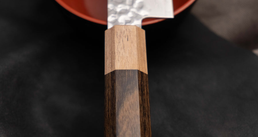 The Kotetsu Sujihiki VG-10 Damascus 240mm (9.5") is a long and narrow Japanese slicer with visible hammer prints, a damascus pattern, and a classic Japanese (wa-style) pakka wood handle. It will impress anyone who appreciates aesthetically designed kitchen utensils.