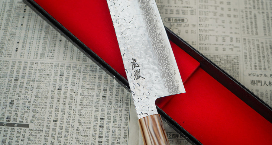 The Kotetsu VG-10 Damascus Nakiri 160 mm is a vegetable knife with visible hammer prints and a classic Japanese (wa-style) teak handle. The knife is extremely thin (1.9mm) so it will slide through ingredients with ease, and the choice of VG-10 stainless steel ensures rust resistance, durability and wear resistance. 