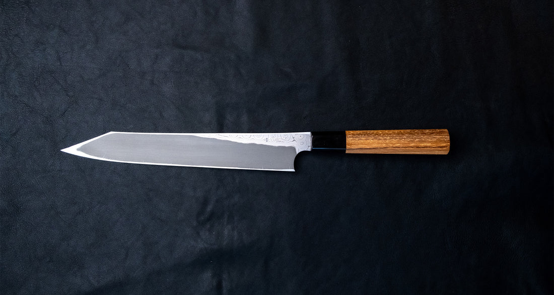 Nigara Kurozome Kiritsuke Yanagiba Aogami #2 Damascus 240mm (9.4") is a traditional single-bevel Japanese knife used for preparing meat and raw fish, especially sashimi&nbsp;and&nbsp;nigiri sushi, and meat. Its length allows the user to slice different types of protein in one single pulling motion, that will – together with the razor-sharp single bevel blade – birth smooth, shiny cuts.