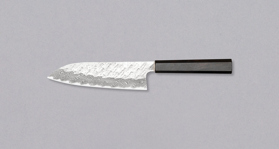 Nigara Santoku VG-10 Damascus Tsuchime is a multi-purpose Japanese kitchen knife, suitable for preparing meat, fish, and vegetables. Its VG-10 stainless steel core ensures a fine sharpness with little to no maintenance. As such, the knife is also suitable as a first Japanese knife or gift. Fitted with ebony handle.