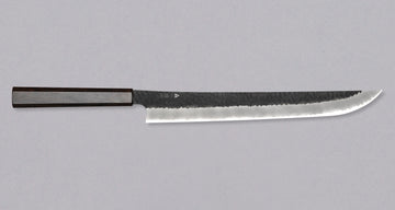 Nigara Sakimaru Sujihiki SG2 Kurouchi Tsuchime 300mm (11.8") [Ebony] is a traditional Japanese knife used for preparing meat and raw fish. It slices protein in one single pulling motion, creating smooth, shiny cuts. Its SG2 powder steel core ensures long-lasting sharpness with little to no maintenance.