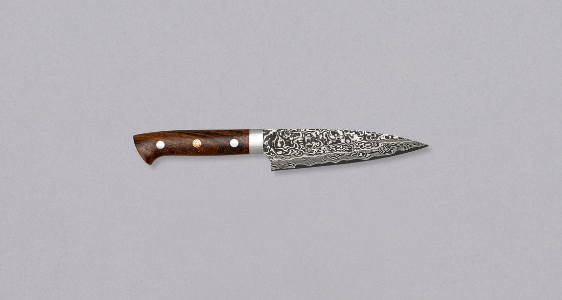 Saji Petty R2 Ironwood 130mm is not just a looker. The core is made of powder R2/SG2 steel, tempered to around 63 HRC, and clad into layers of rust-resistant stainless steel which creates a unique damascus pattern. The knife is stored in a traditional Japanese wooden box with burned Saji trademark kanji on top.