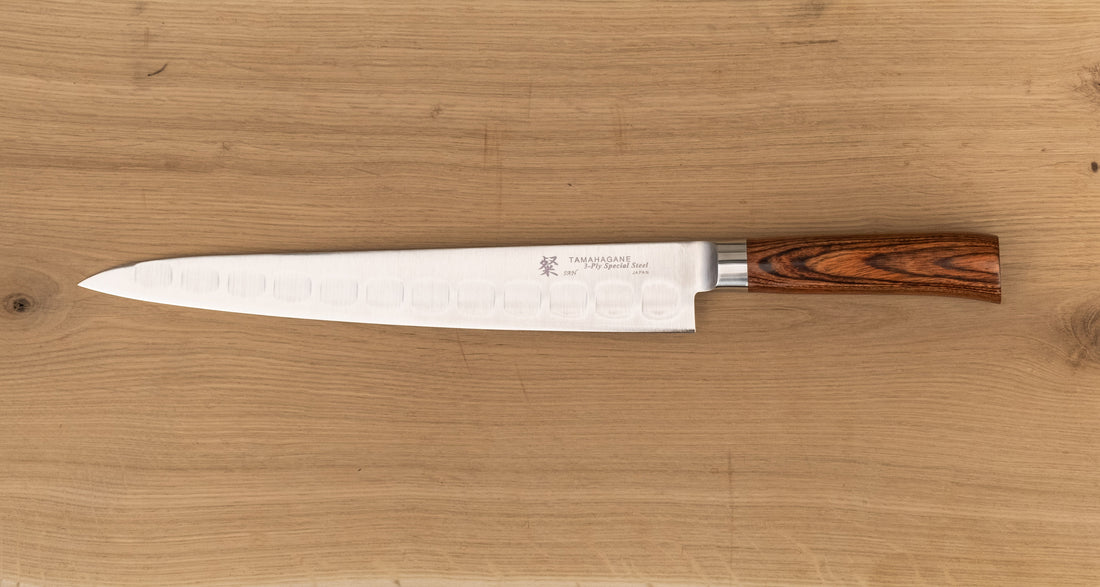 Tamahagane San Sujihiki (or slicer) knife is primarily intended for long pulls and precise cuts of meat and fish. Dimples on the blade also have a practical function: the air in the clefts acts as an anti-stick coating between the knife and the food and reduces the drag during cutting.