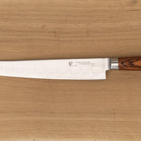 Tamahagane San Sujihiki (or slicer) knife is primarily intended for long pulls and precise cuts of meat and fish. Dimples on the blade also have a practical function: the air in the clefts acts as an anti-stick coating between the knife and the food and reduces the drag during cutting.