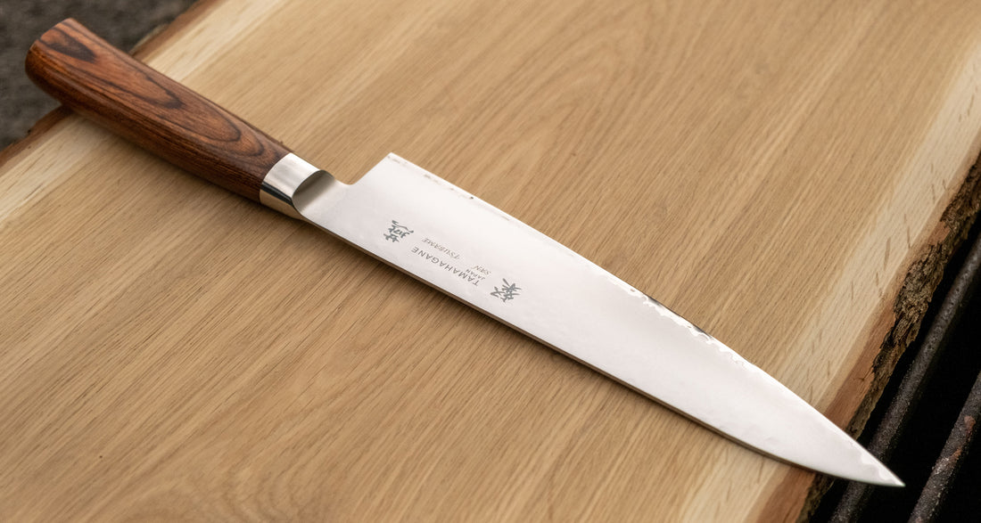 Tamahagane Gyuto is an all-rounder when it comes to knives, designed for a wide range of kitchen tasks. It will excel at chopping vegetables and slicing larger cuts of meat. The narrow tip can be used for tasks where precision is key. A true workhorse, that will ease long hours of food prep in a professional kitchen. The core of the blade has a high-polish finish and is forged out of VG-5 (High Carbon Molybdenum Vanadium Steel) steel hardened to 61 HRC. 