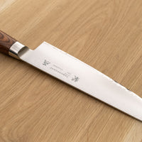 Tamahagane Gyuto is an all-rounder when it comes to knives, designed for a wide range of kitchen tasks. It will excel at chopping vegetables and slicing larger cuts of meat. The narrow tip can be used for tasks where precision is key. A true workhorse, that will ease long hours of food prep in a professional kitchen. The core of the blade has a high-polish finish and is forged out of VG-5 (High Carbon Molybdenum Vanadium Steel) steel hardened to 61 HRC. 