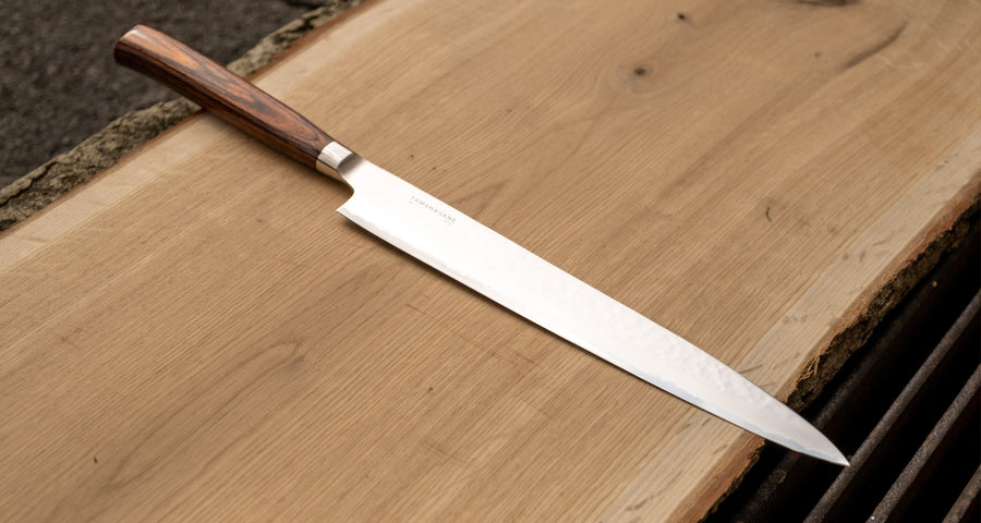 Tamahagane Tsubame Slicer knife is primarily intended for long pulls and precise cuts of meat and fish. The 240mm (9.5") version is designed for medium-sized fish and pieces of meat. A matte blade finish, featured with the core VG-5 steel hardened to 61 HRC.