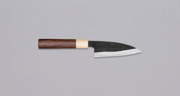 This Ajikiri SUJ-2 blade made by Yoshida Hamono is a Japanese knife for small fish. It's fitted with an oval rosewood handle which is topped with a cedar ferrule. The blade is forged from SUJ-2 steel with a hardness is 63-64 HRC, which holds its edge for a long time and is very easy to resharpen.