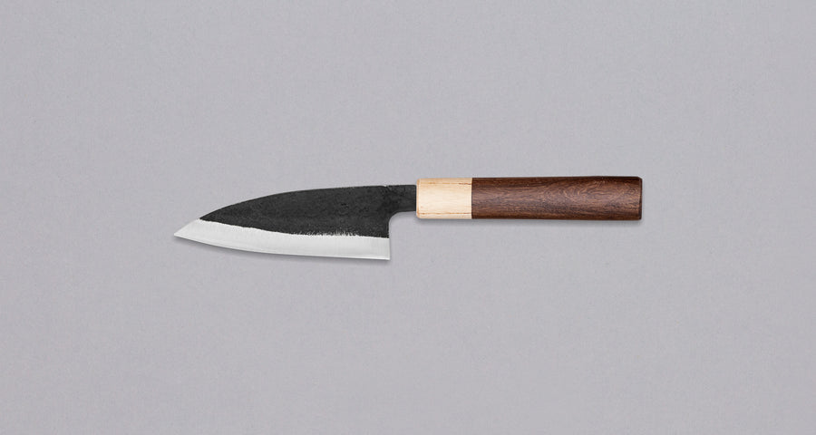 This Ajikiri SUJ-2 blade made by Yoshida Hamono is a Japanese knife for small fish. It's fitted with an oval rosewood handle which is topped with a cedar ferrule. The blade is forged from SUJ-2 steel with a hardness is 63-64 HRC, which holds its edge for a long time and is very easy to resharpen.