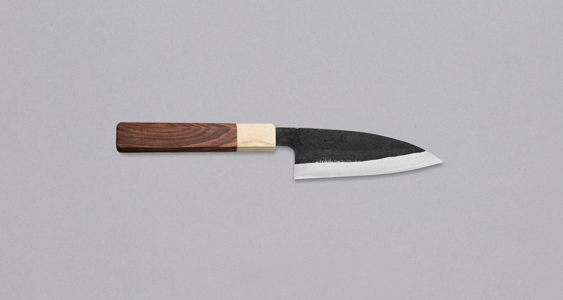 This Ajikiri SUJ-2 blade made by Yoshida Hamono is a Japanese knife for small fish. It's fitted with an octagonal rosewood handle which is topped with a cedar ferrule. The blade is forged from SUJ-2 steel with a hardness is 63-64 HRC, which holds its edge for a long time and is very easy to resharpen.