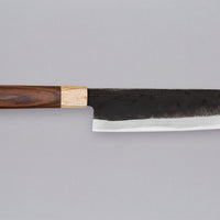 This Nakiri Kyusyu SUJ-2 blade is fitted with an oval rosewood handle, topped with a cedar ferrule. A traditional Japanese knife for cutting vegetables. The blade is forged from SUJ-2 steel with a hardness is 63-64 HRC, which holds its edge for a long time and is very easy to resharpen.