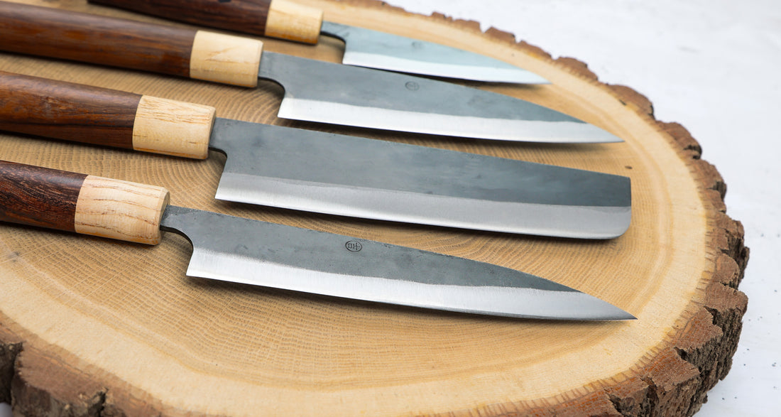 Full Yoshida hamono Japanese knife line from SUJ2 steel fitted with a rosewood and cedar japanese handle.  Currently on offer -  from the left: ajikiri, santoku, nakiri, utility