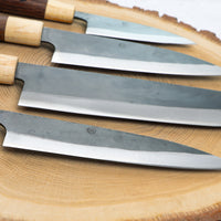 Full Yoshida hamono Japanese knife line from SUJ2 steel fitted with a rosewood and cedar japanese handle.  Currently on offer -  from the left: ajikiri, santoku, nakiri, utility