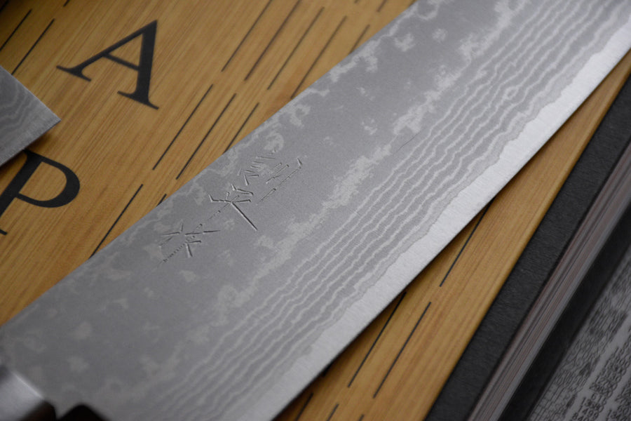 Etsu Village Damascus Santoku Black 170mm (6.7")_2  Damascus Santoku Black features a Western-style (Yo) handle from black micarta. This knife will be a great addition to your kitchen, suitable for cutting veggies, meat and fish. Blacksmith Masutani is known as an incredibly good knife sharpener, and his knives are no different, featuring a very thin spine (around 1.8mm).
